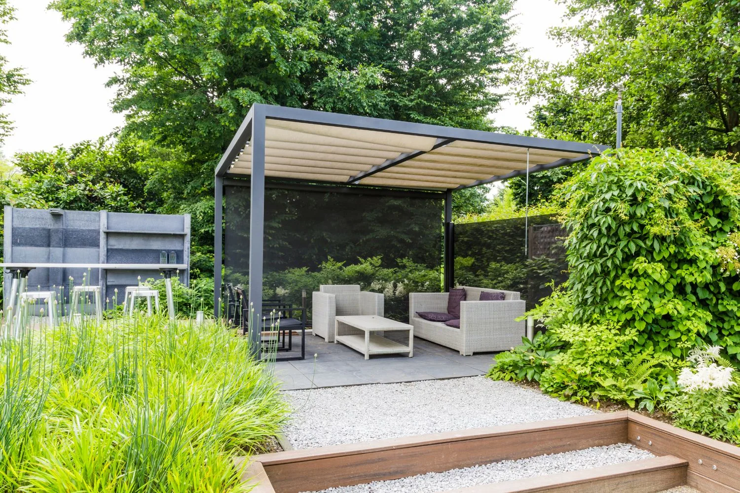 A freestanding louvred pergola over an outdoor lounge setting
